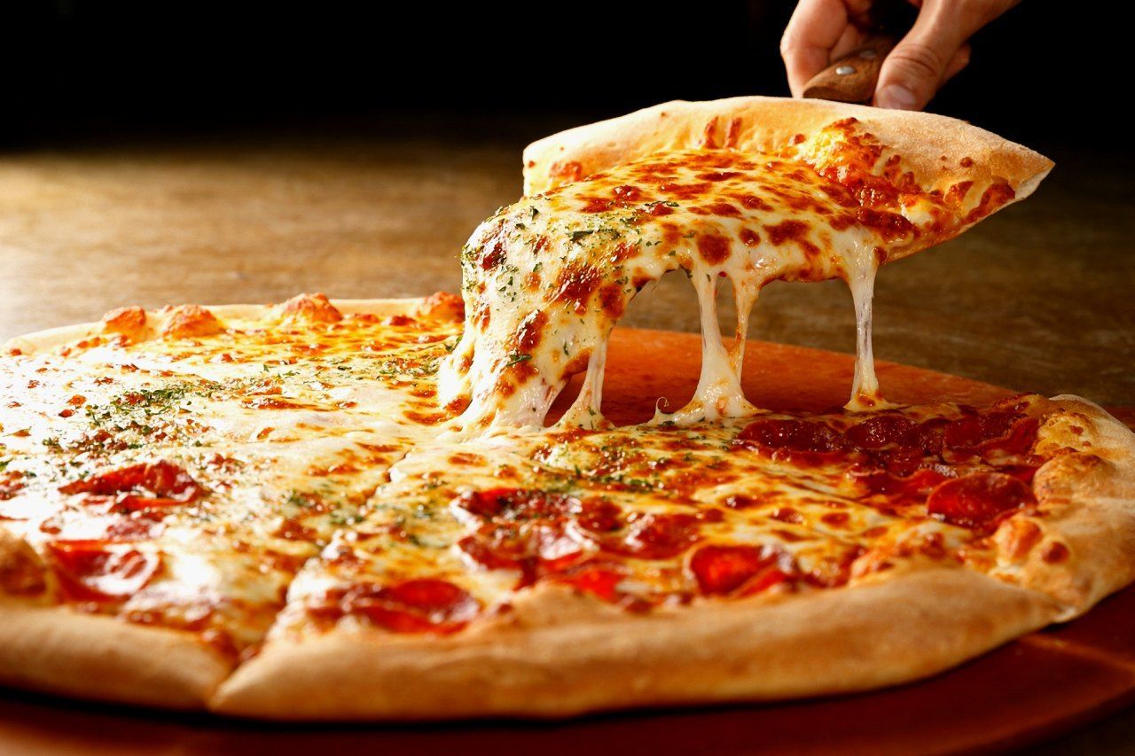 Uma pessoa está pegando um pedaço de pizza de uma pizza.