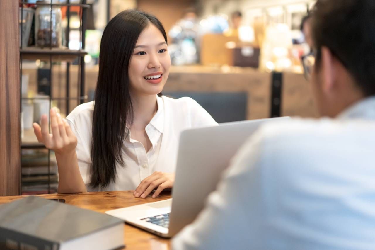Um homem e uma mulher estão sentados à mesa com um laptop.