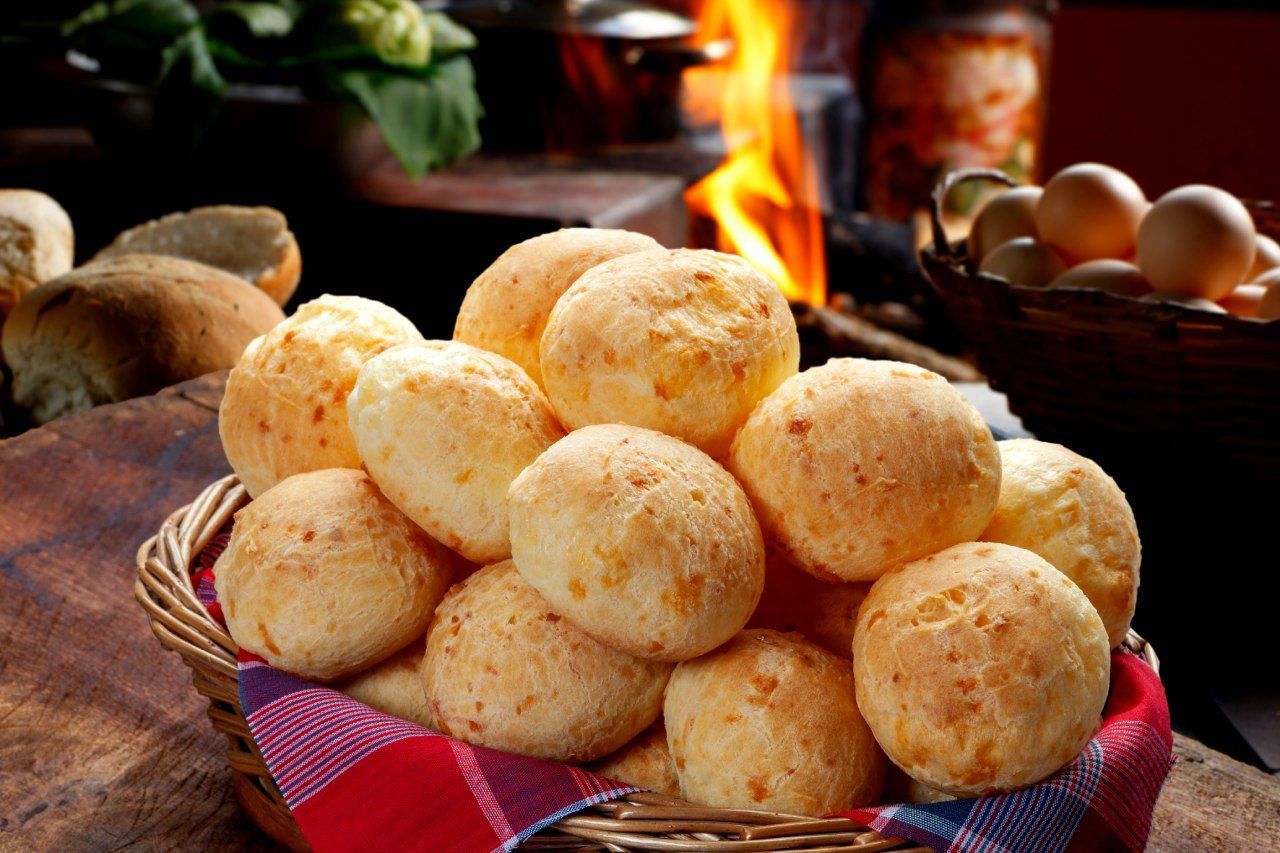 Uma cesta de bolinhas de queijo está sobre uma mesa de madeira.