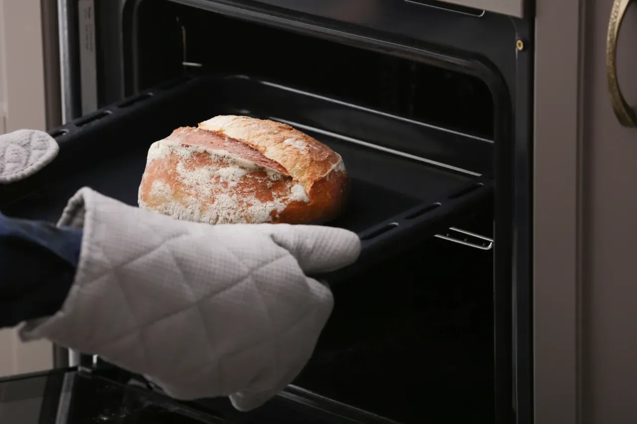 Uma pessoa está tirando um pão do forno.