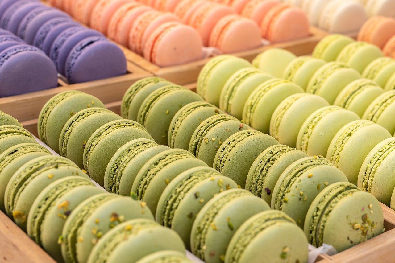 Uma bandeja de madeira cheia de muitos macarons coloridos diferentes.