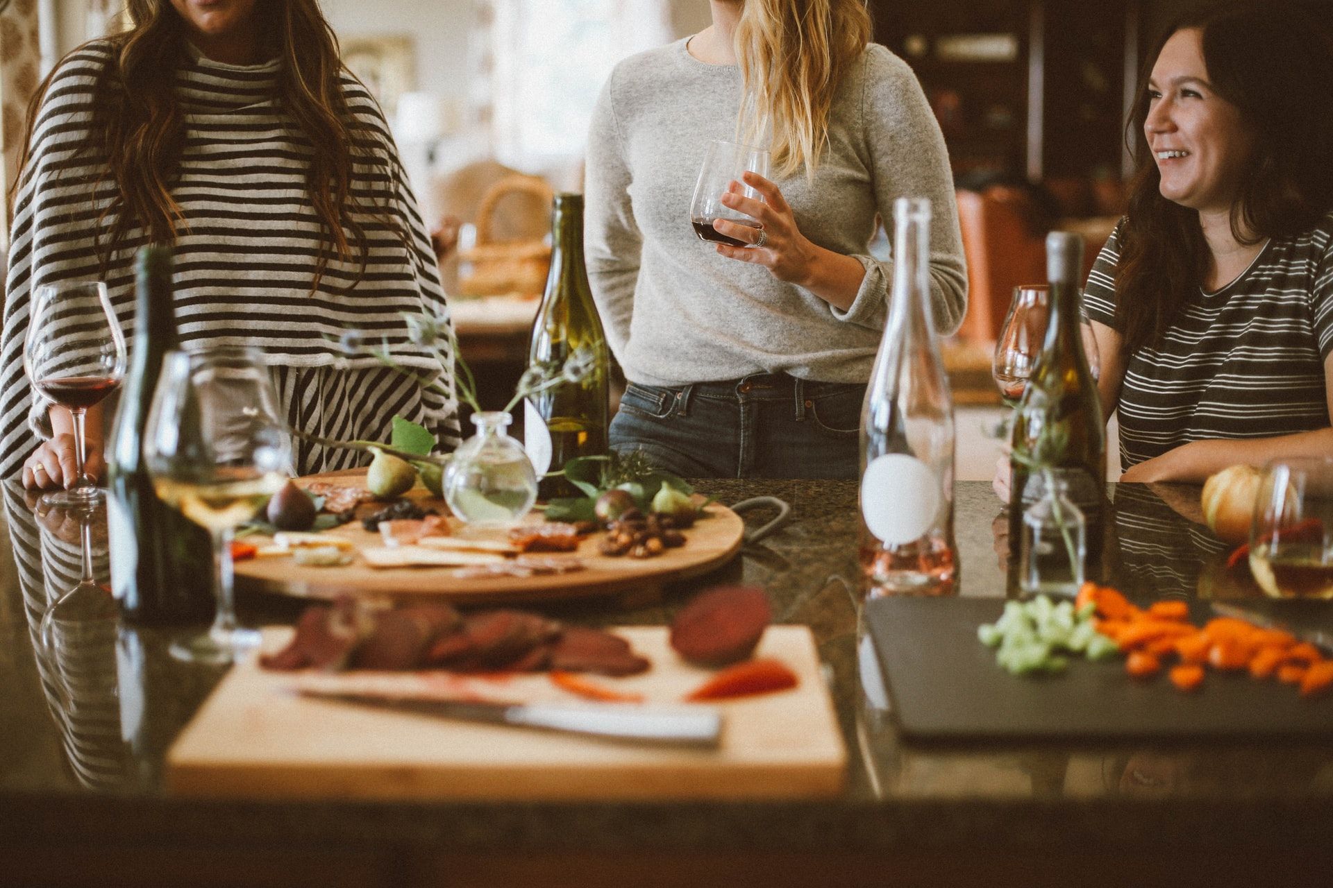 Um grupo de mulheres está em volta de uma mesa com comida e bebidas.