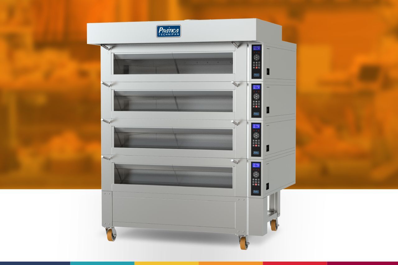 Um grande forno de aço inoxidável com rodas está sobre uma mesa.
