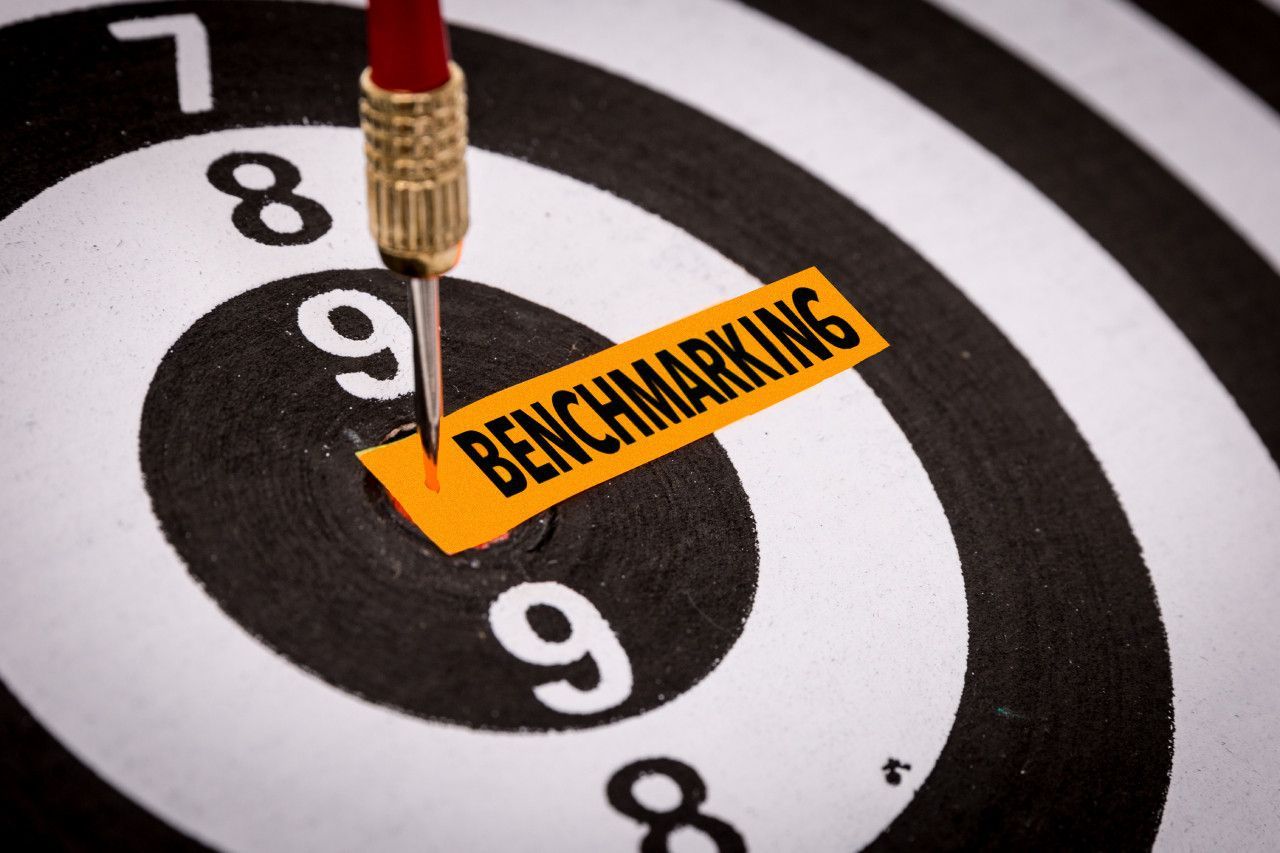 Um dardo está atingindo o centro de um alvo que diz benchmarking