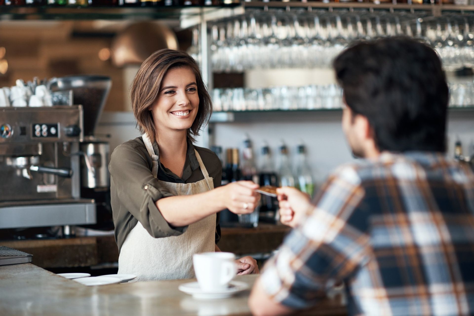 Uma mulher está dando um cartão de crédito a um homem em um restaurante.