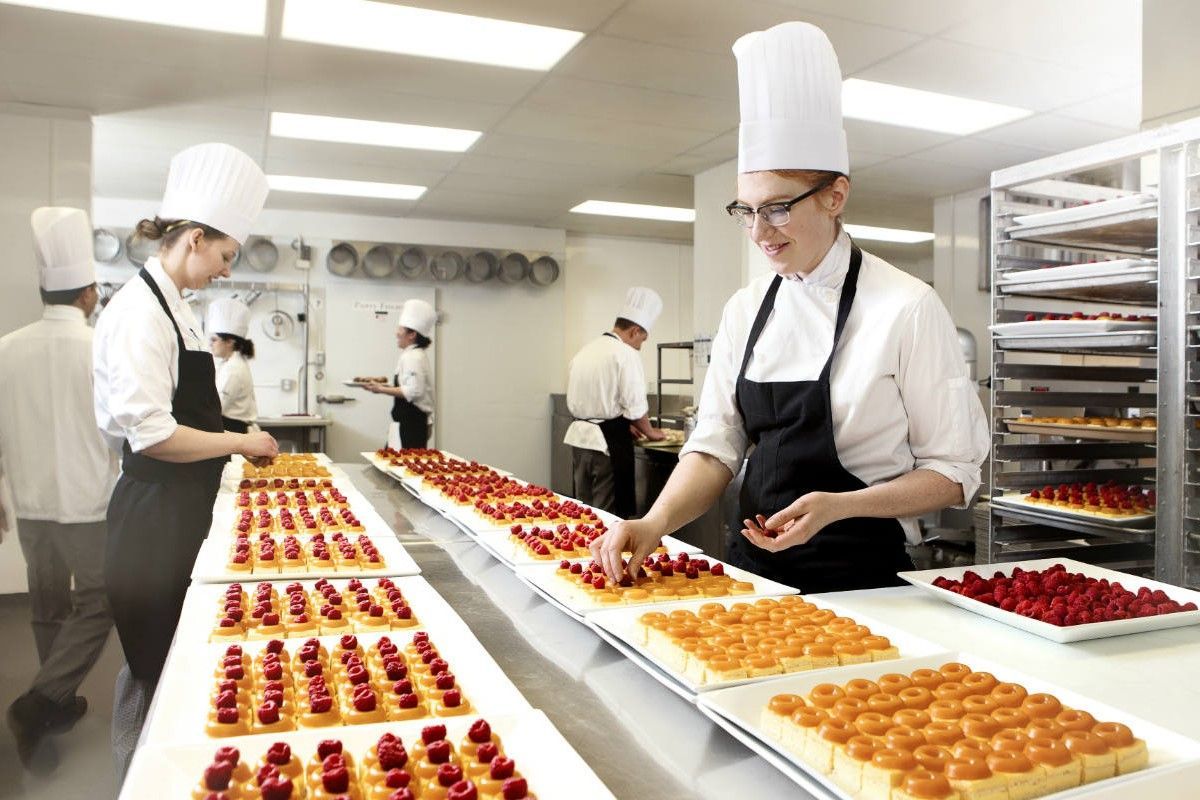 Um grupo de chefs está preparando sobremesas em uma cozinha