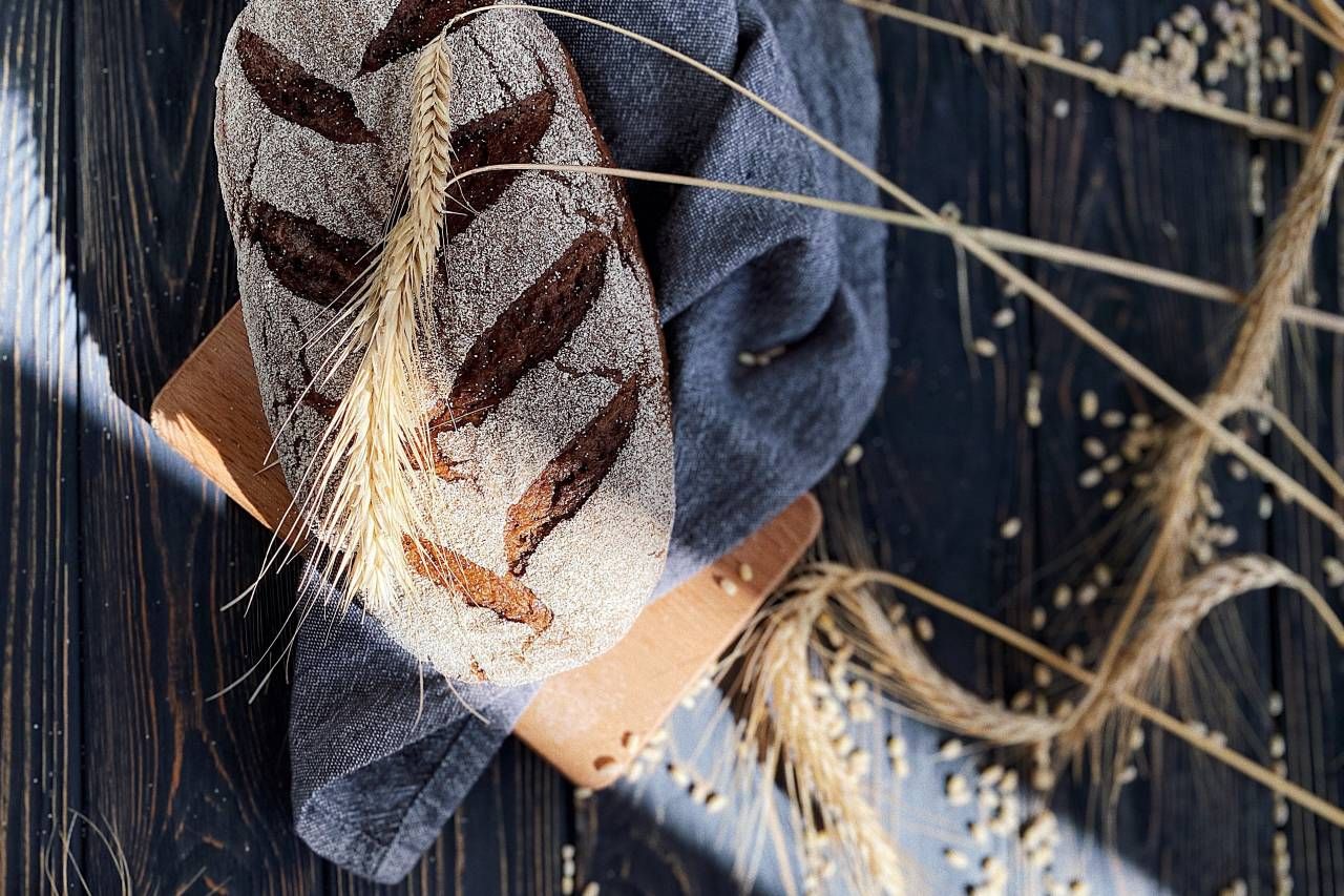 Um pedaço de pão está sobre uma tábua de corte de madeira em uma mesa de madeira.