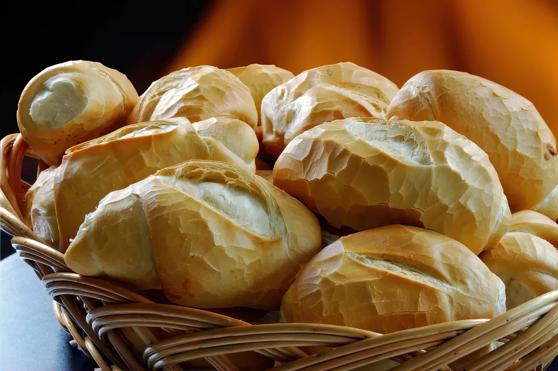 Uma cesta cheia de pãezinhos sobre uma mesa
