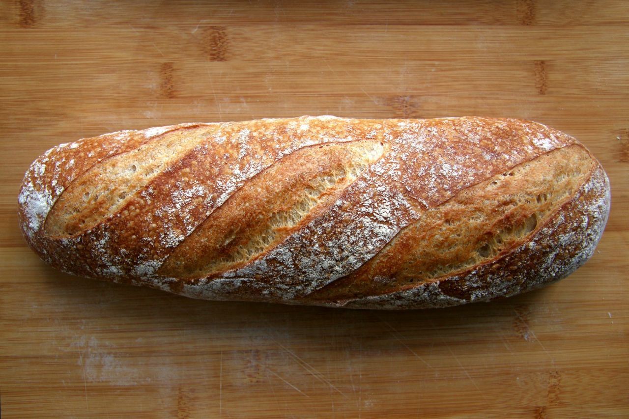 Um pedaço de pão está sobre uma tábua de corte de madeira.