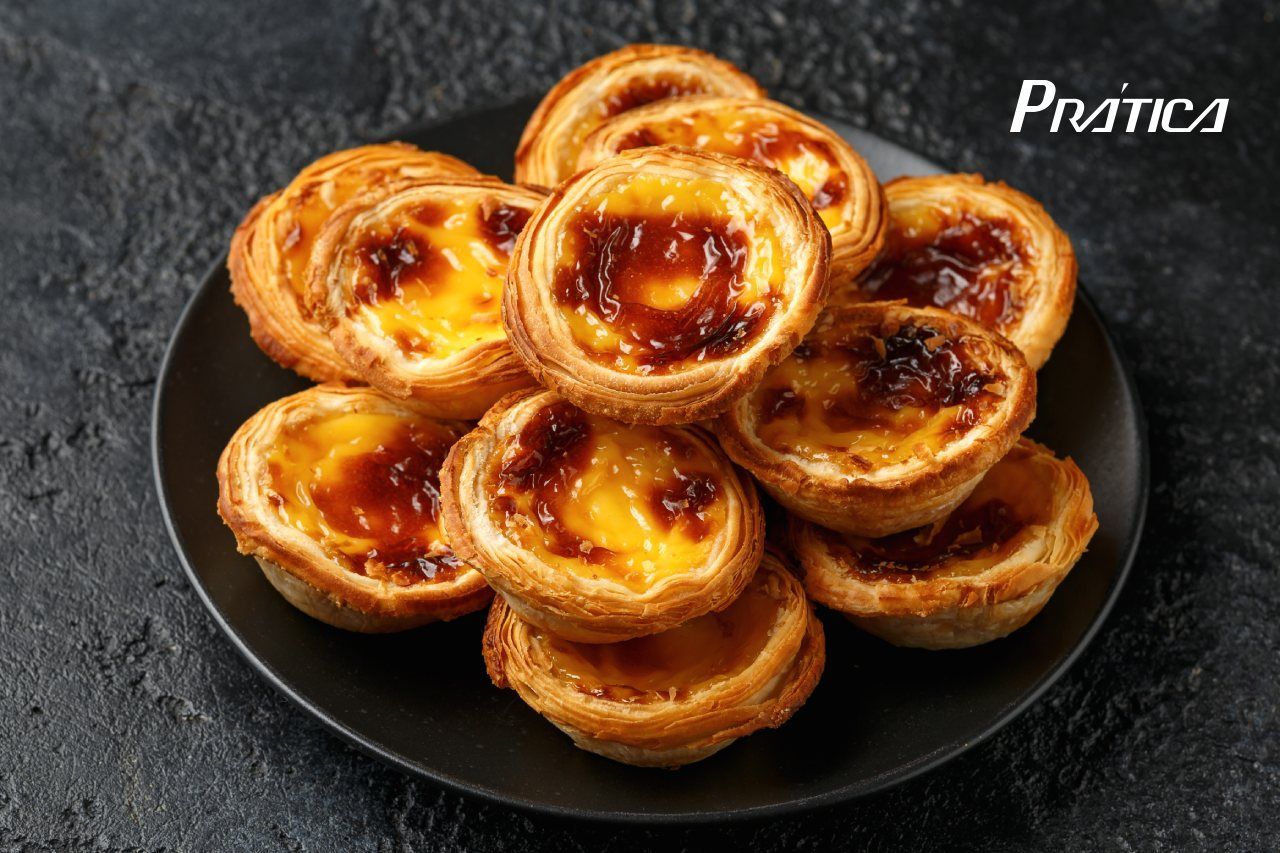Um prato preto coberto com uma pilha de pastéis de nata.