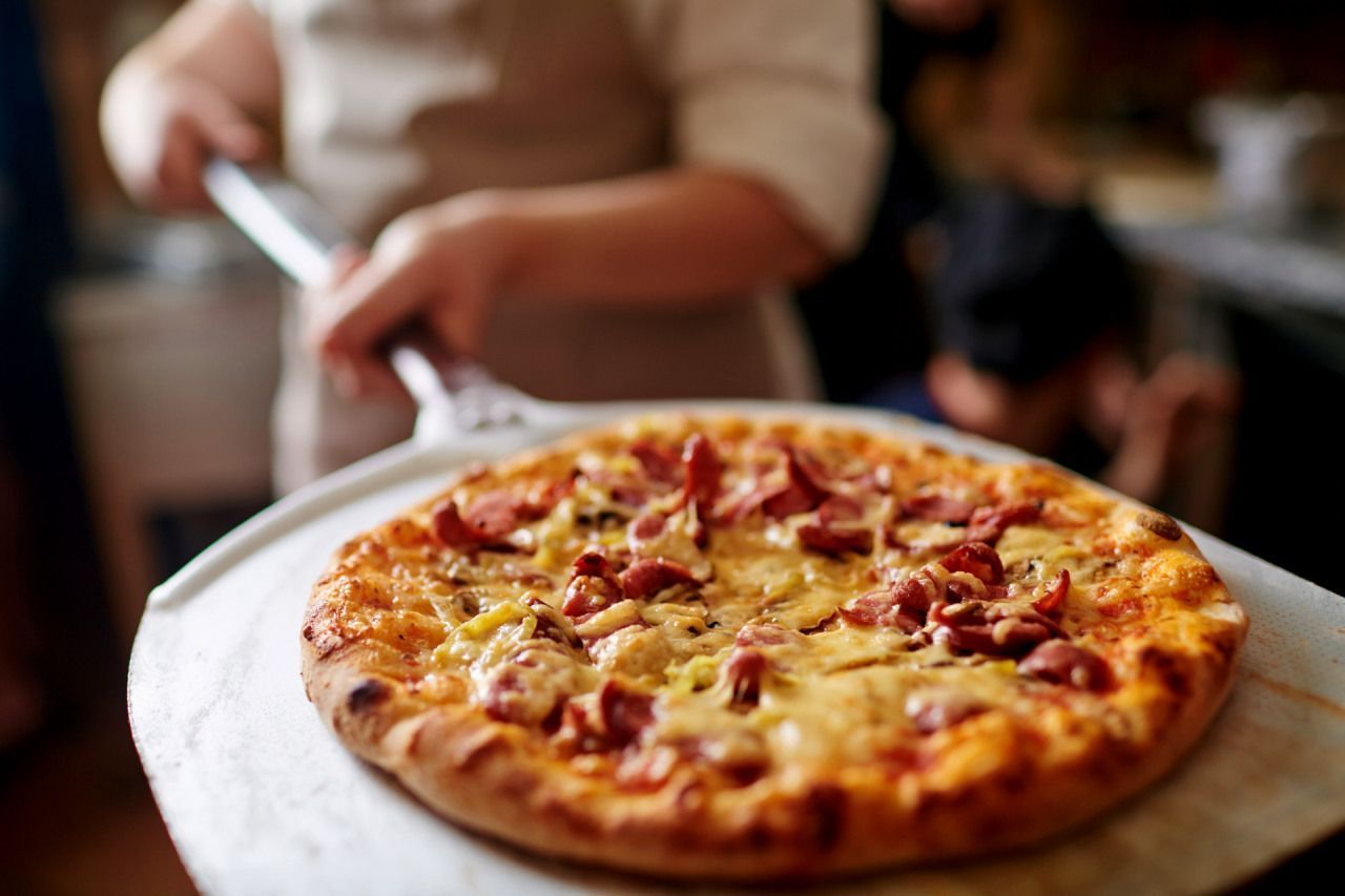 Uma pessoa está segurando uma pizza em uma pá.