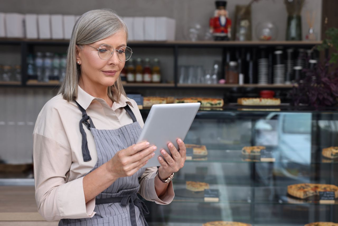 Uma mulher está usando um tablet em uma padaria.