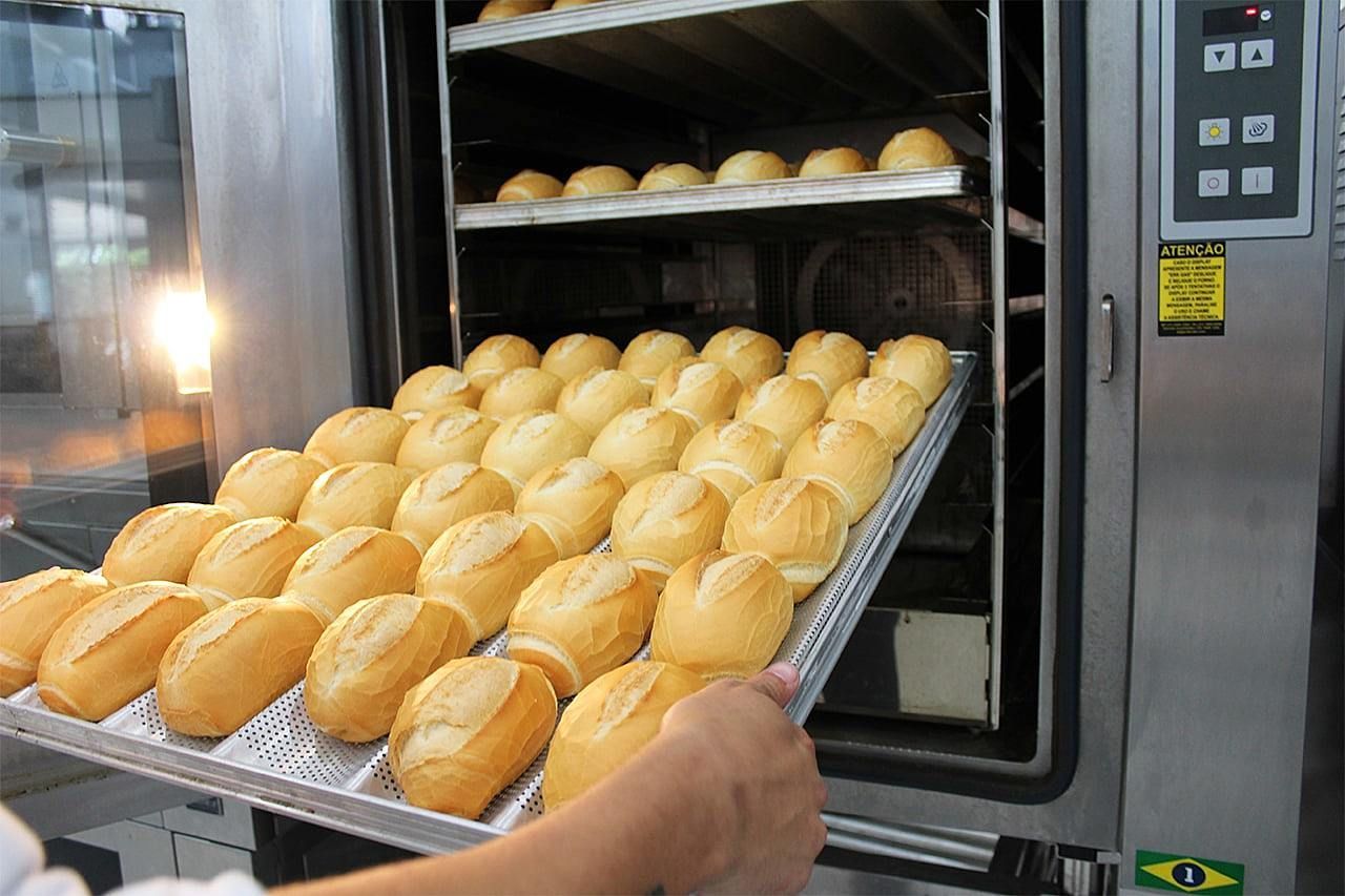 Uma pessoa está tirando uma bandeja de pão do forno