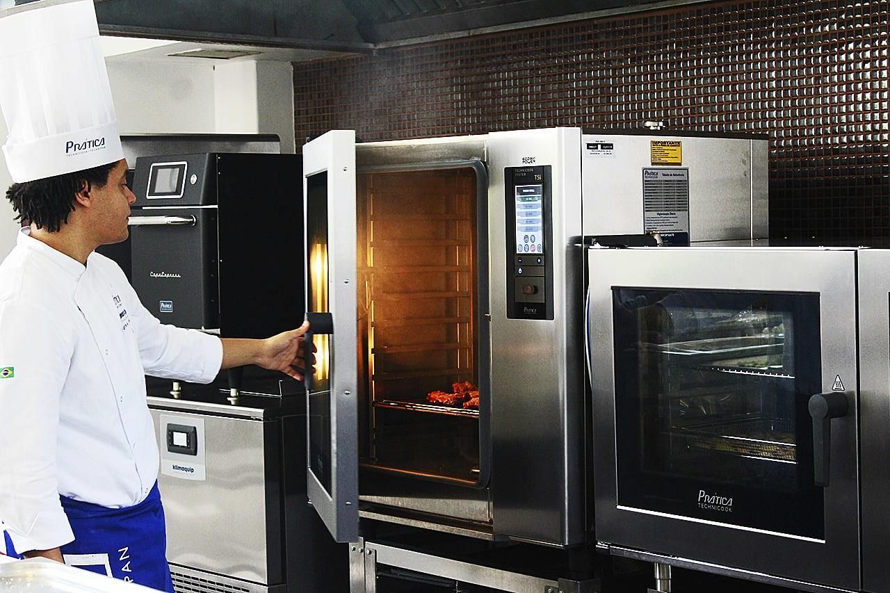 Um homem com chapéu de chef está abrindo um forno