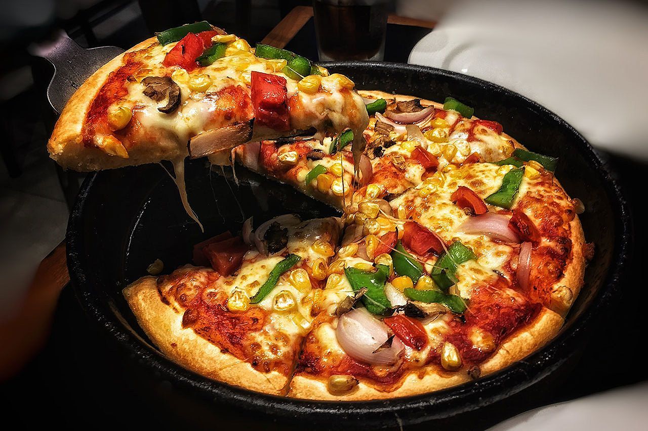 Uma fatia de pizza está sendo retirada de uma assadeira de pizza.