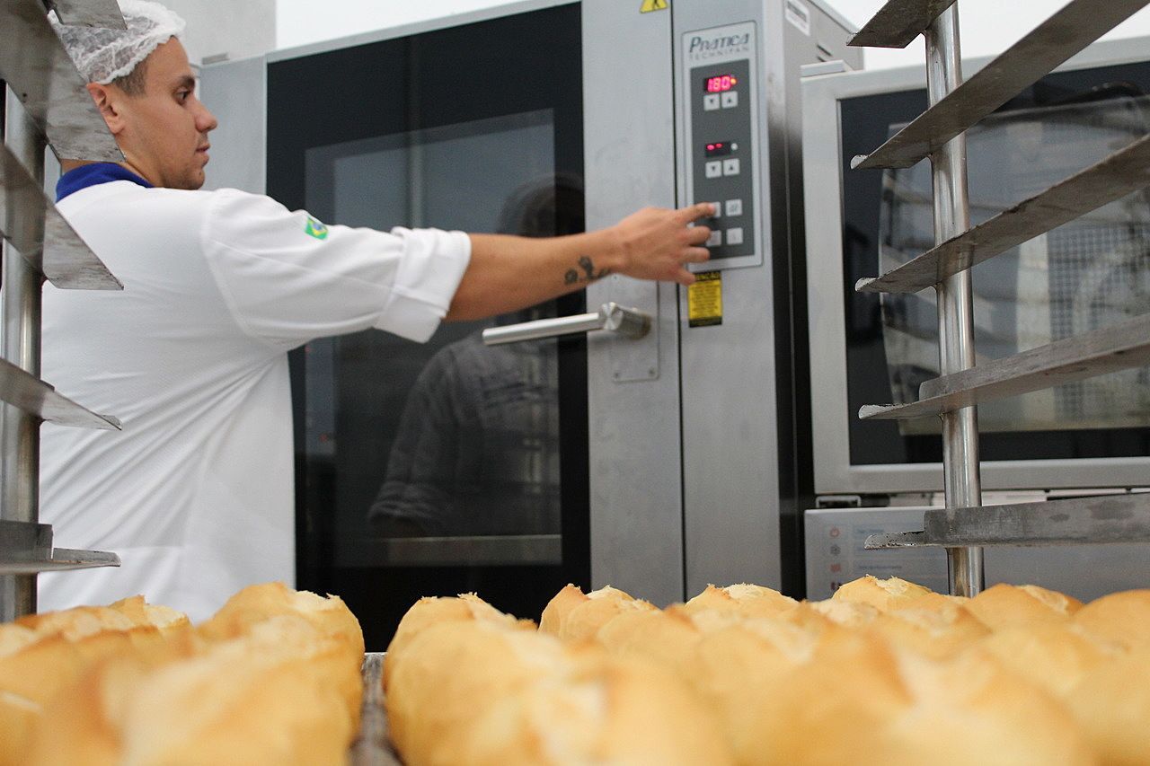 Um homem está apertando um botão de um forno em uma padaria