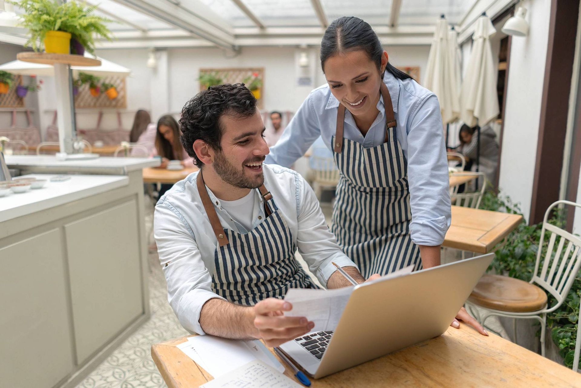Um homem e uma mulher estão olhando para um laptop em um restaurante.