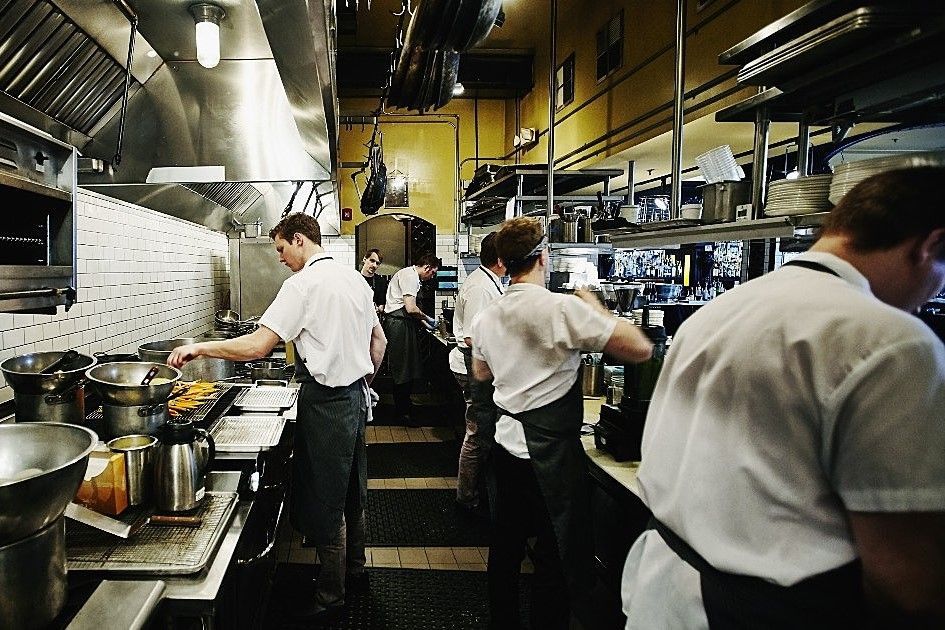 Um grupo de homens está trabalhando em uma cozinha preparando comida