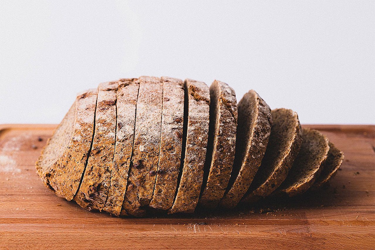 Um pedaço de pão está sobre uma tábua de corte de madeira.