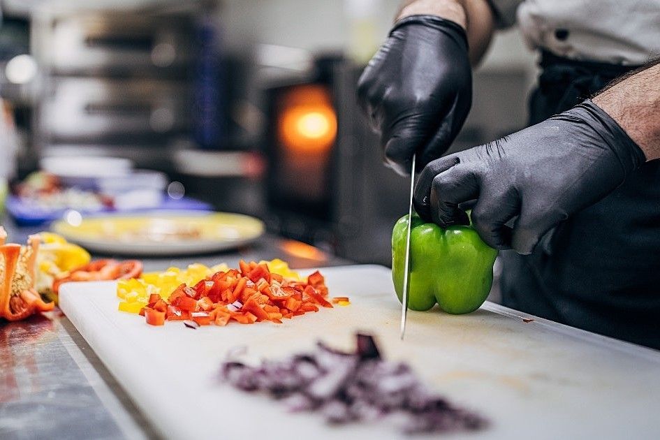 Um chef está cortando vegetais em uma tábua de corte na cozinha.