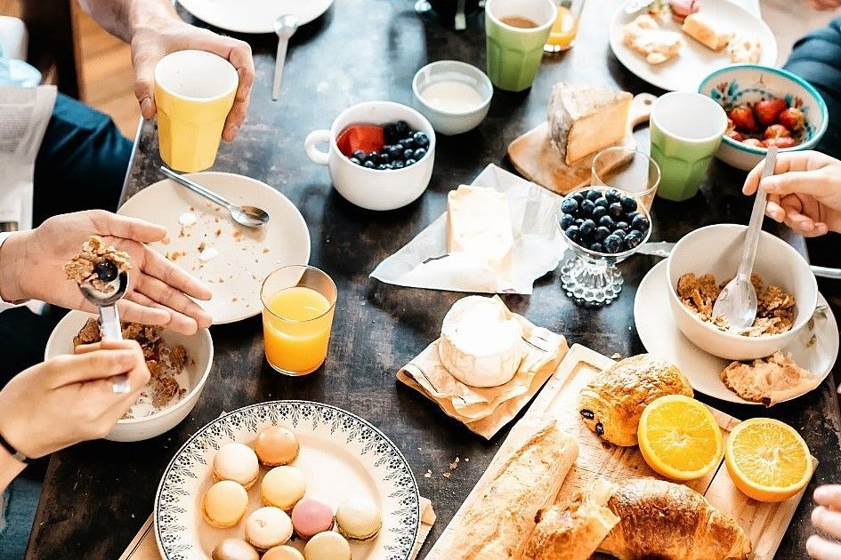 Um grupo de pessoas está sentado ao redor de uma mesa tomando café da manhã.