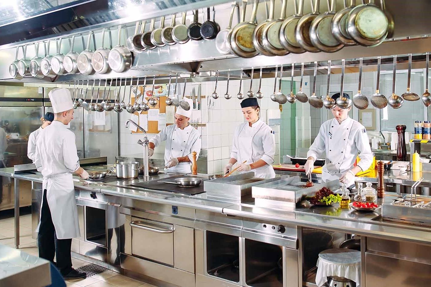 Um grupo de chefs está preparando comida em uma cozinha comercial.