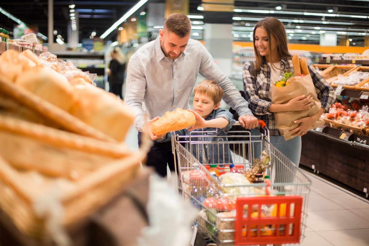 Uma família está fazendo compras em um supermercado e empurrando um carrinho de compras.