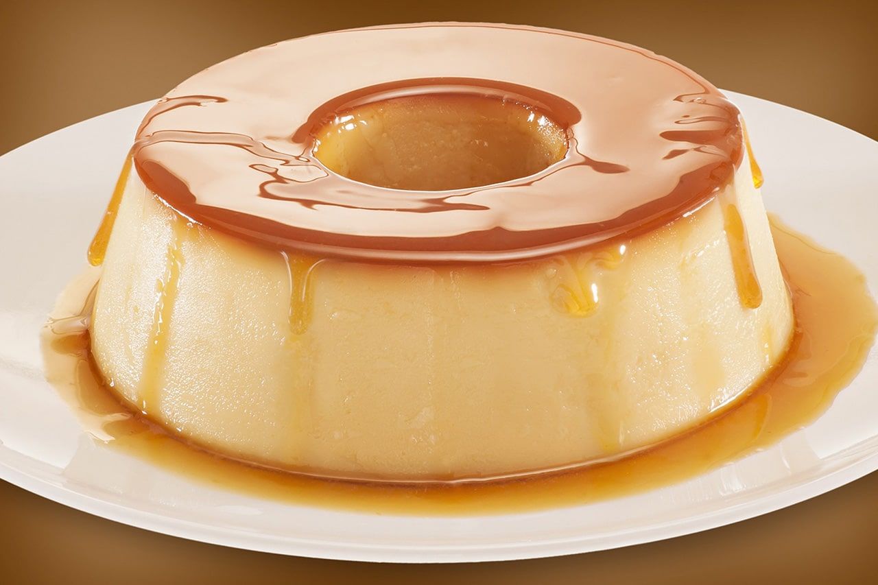 Um prato branco coberto com pudim e calda de caramelo