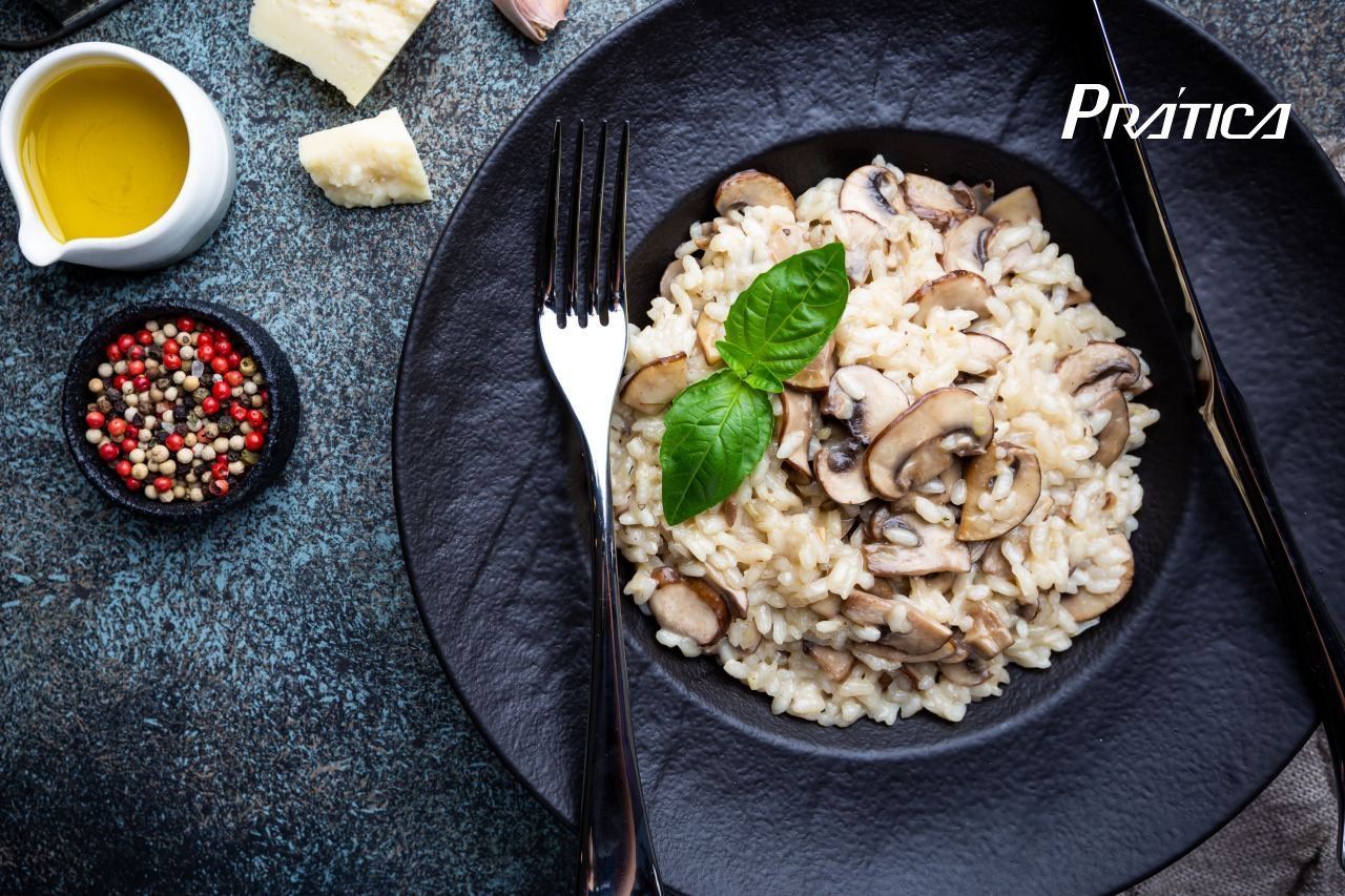 Um prato preto coberto com arroz e cogumelos com um garfo.