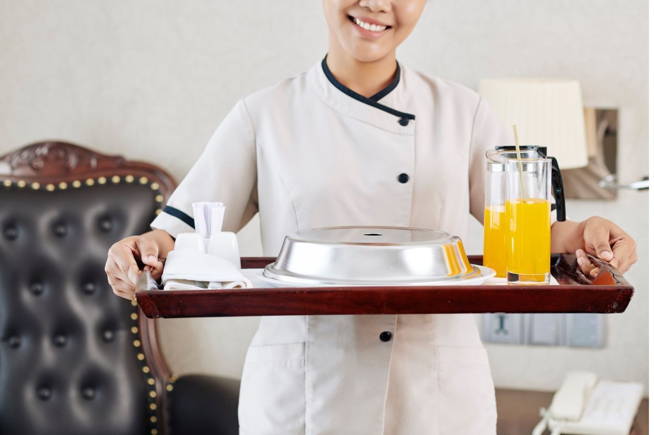 Uma mulher está segurando uma bandeja com uma jarra de suco de laranja.