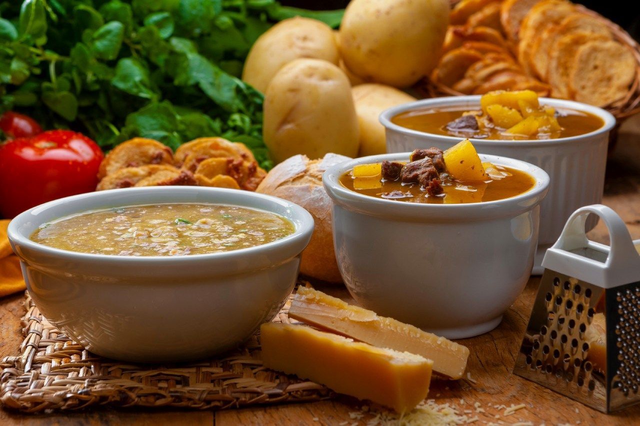 Três tigelas de sopa estão sobre uma mesa de madeira.
