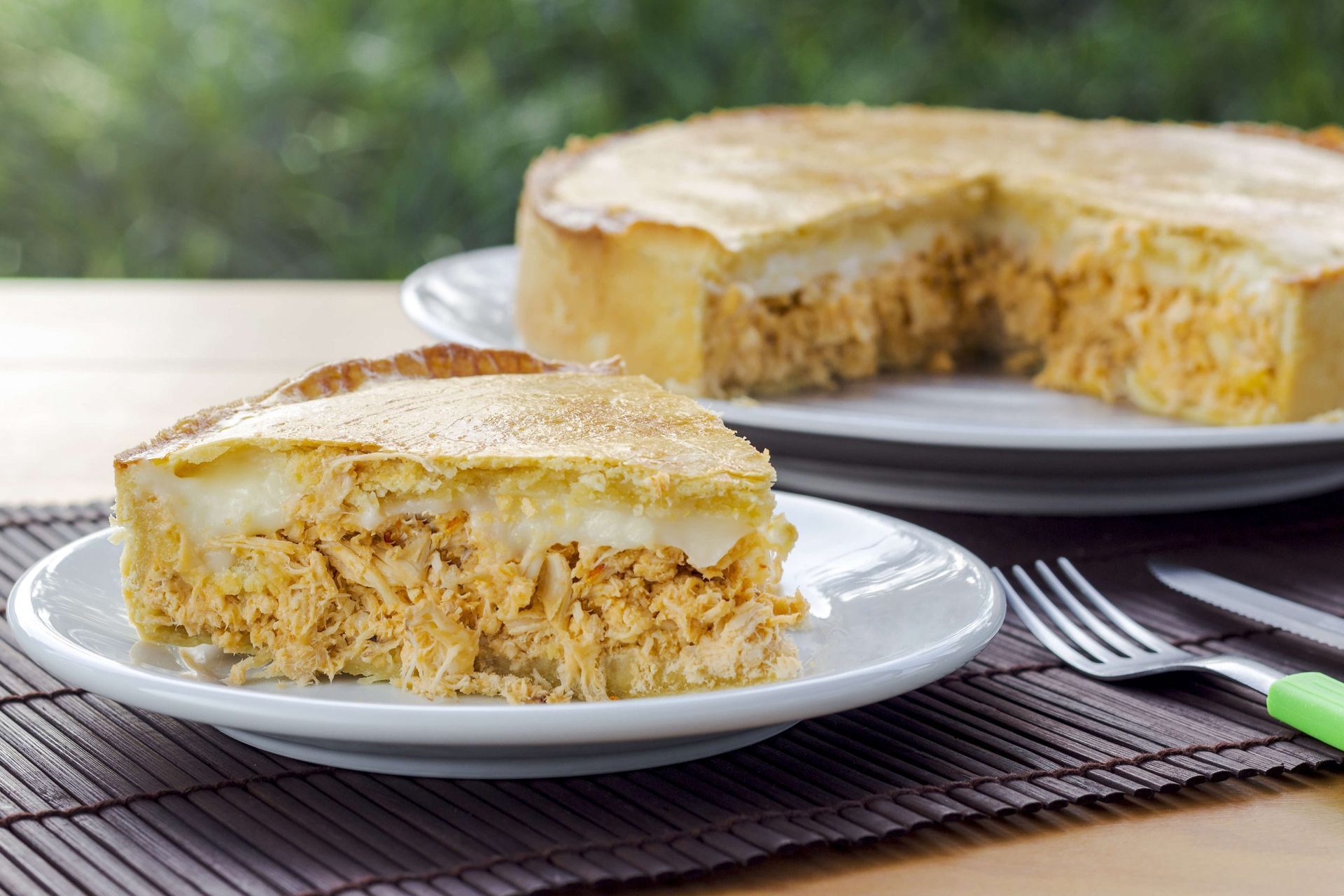 Uma torta com uma fatia retirada dela está em um prato sobre uma mesa.