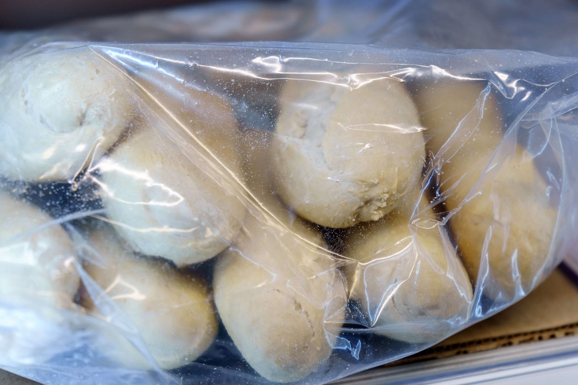 Um saco plástico cheio de batatas está sobre uma mesa.
