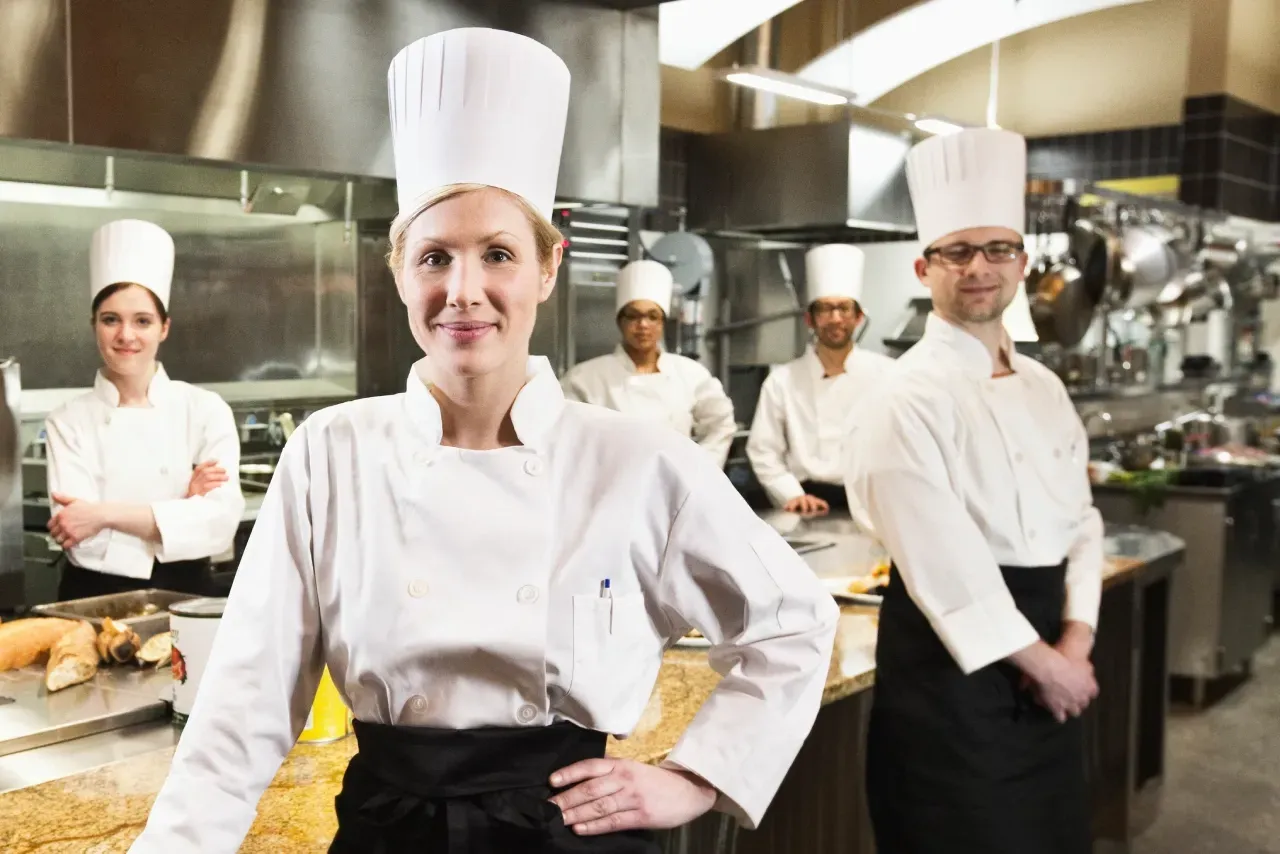 Um grupo de chefs está posando para uma foto em uma cozinha.