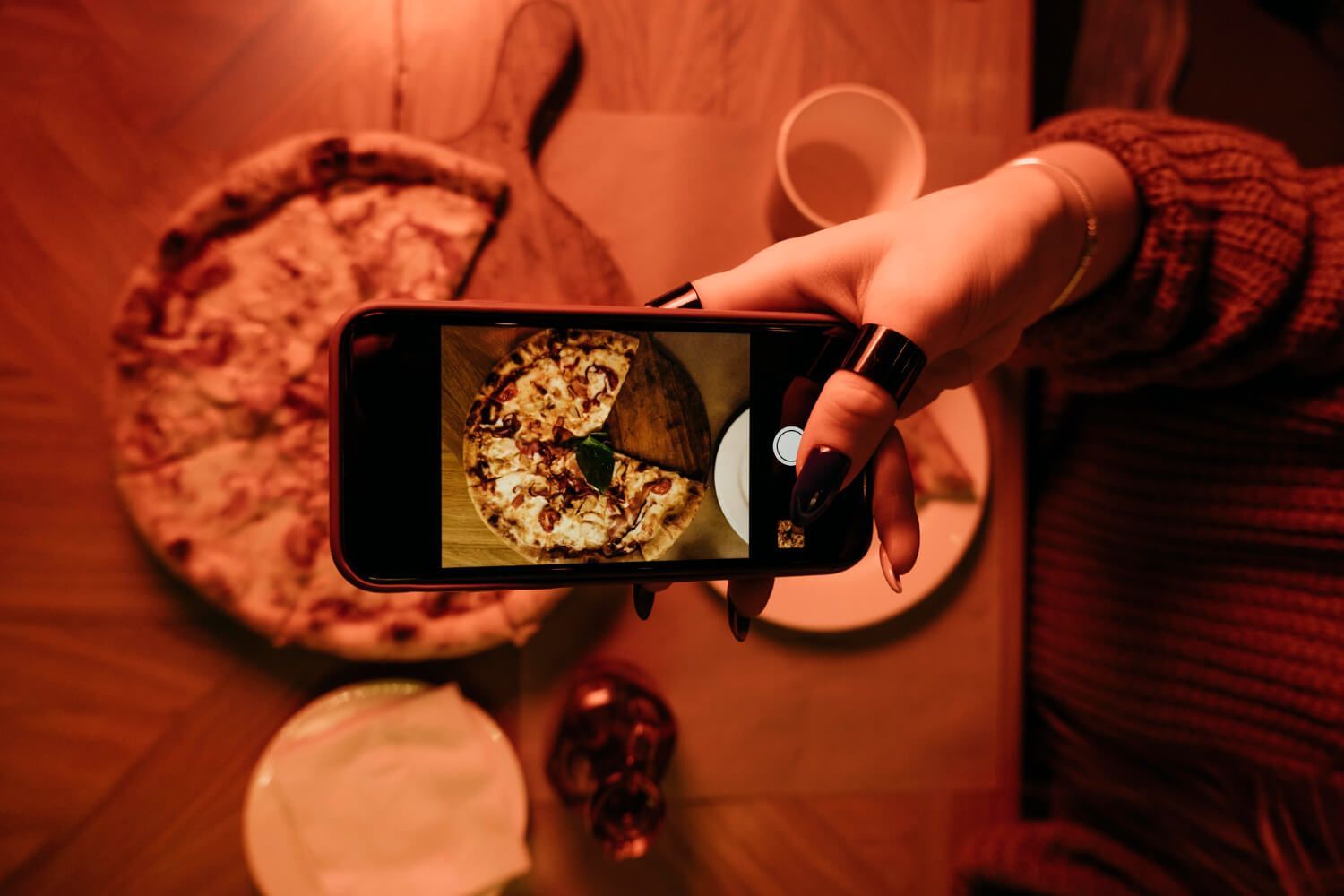 Uma pessoa está tirando uma foto de uma pizza com um celular.