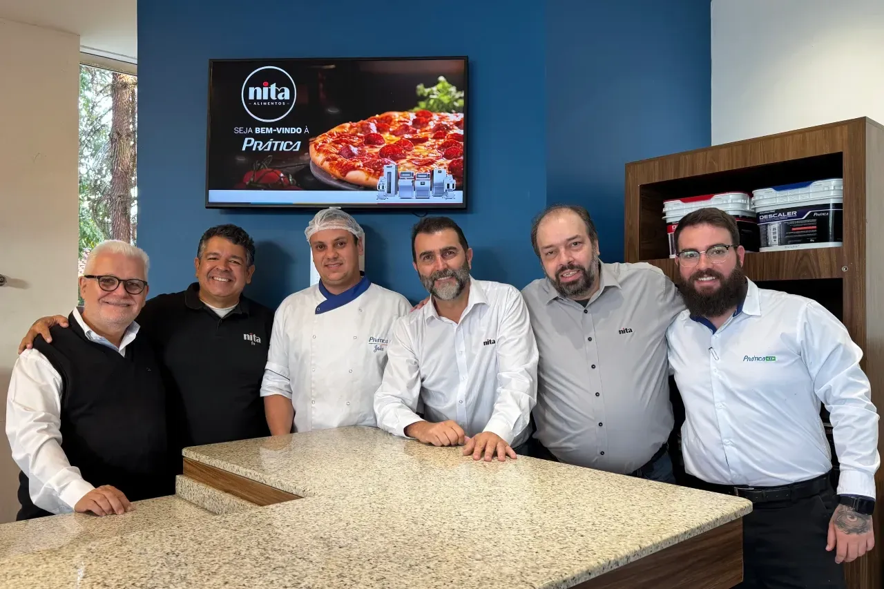 Um grupo de homens está posando para uma foto em pé ao redor de um balcão.
