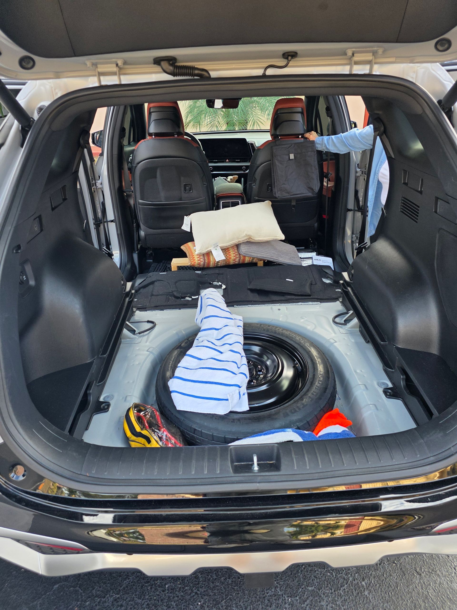 SUV trunk with bare cargo area, spare tire, striped towel, and small items, seats folded down
