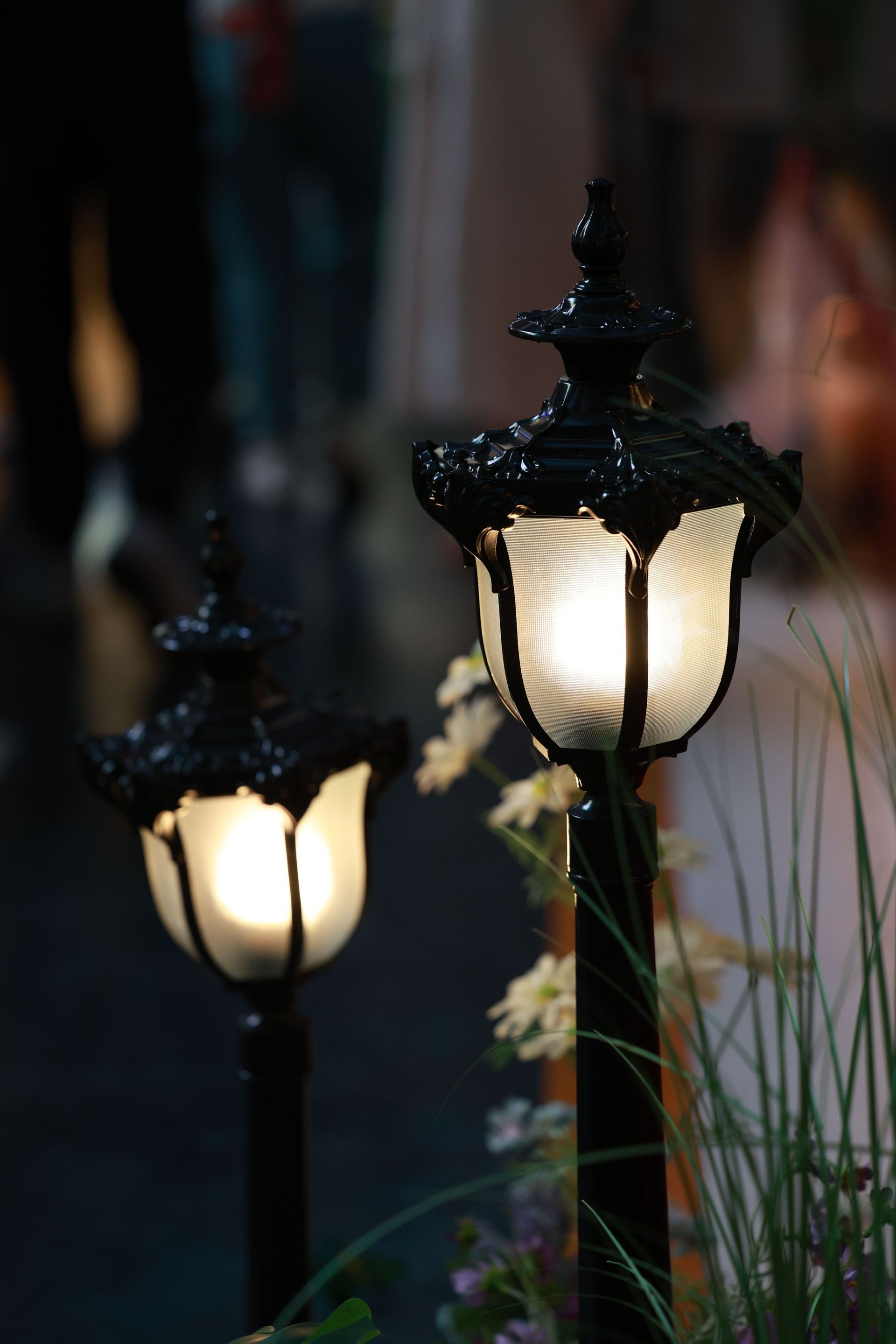 Two glowing vintage-style street lamps at night with softly blurred background lights
