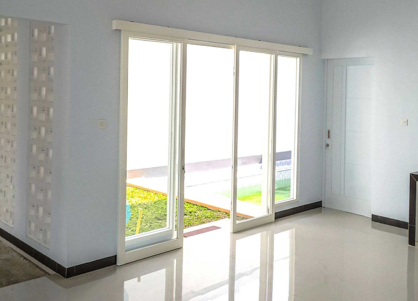 Bright interior with sliding glass doors, light blue walls, and shiny tile floor.
