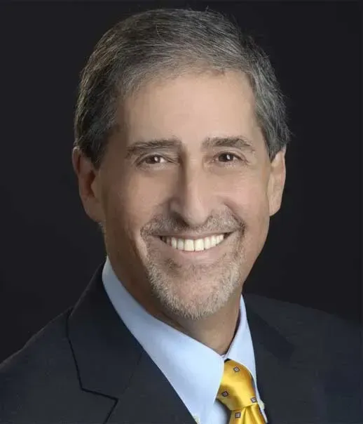 A man in a suit and tie is smiling for the camera
