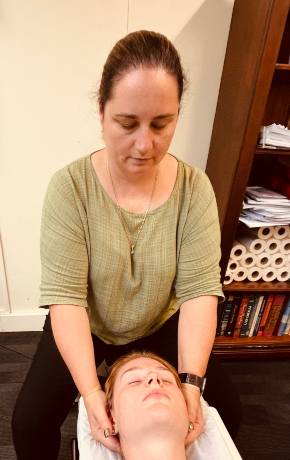 Woman providing neck massage to another person, hands on head; in office setting — Axis Chiropractic In Cairns City, QLD