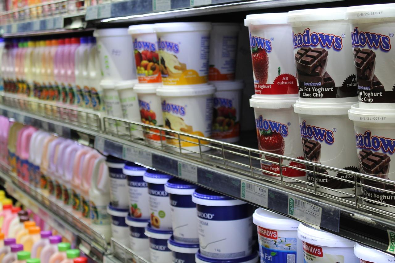 a shelf in a grocery store refrigerator filled with various types of yogurt