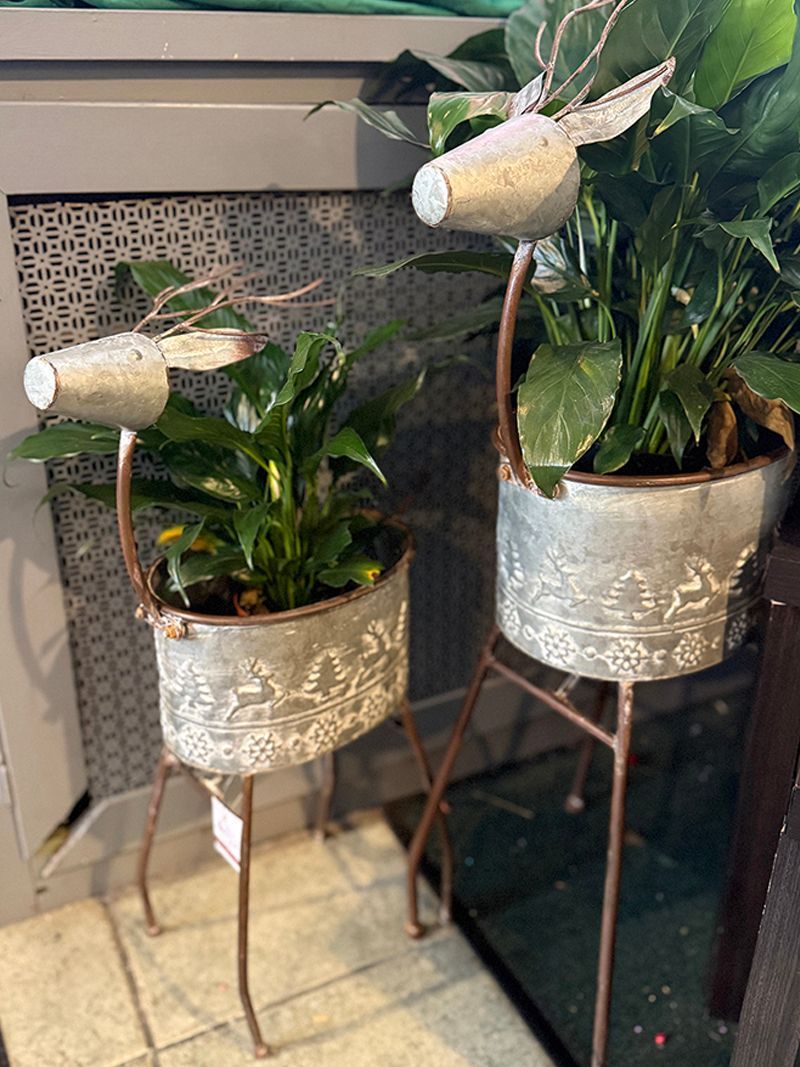 A red and white striped vase filled with a plant and christmas ornaments.
