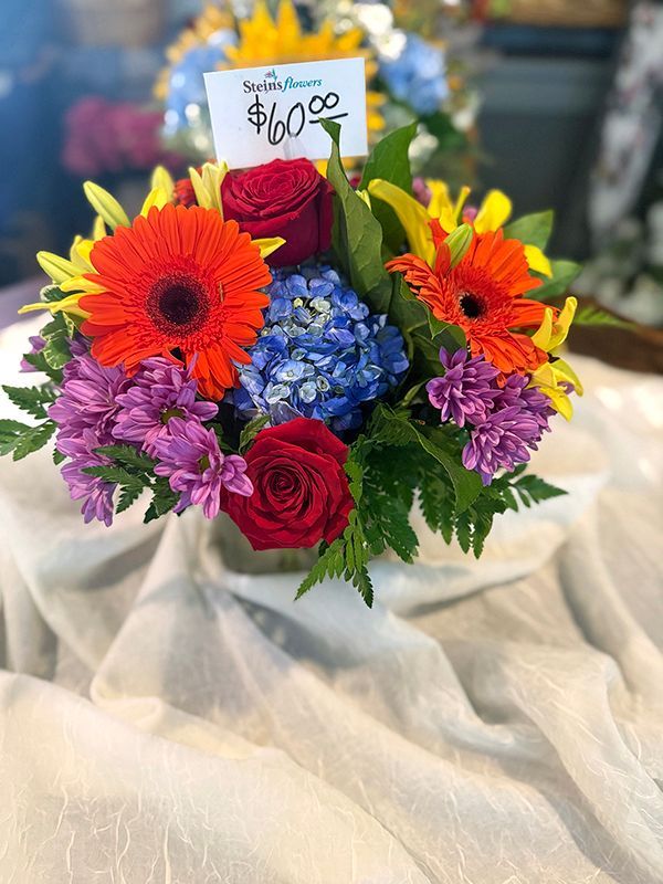 Colorful mixed-flower bouquet in a wrapped vase with a price tag on top
