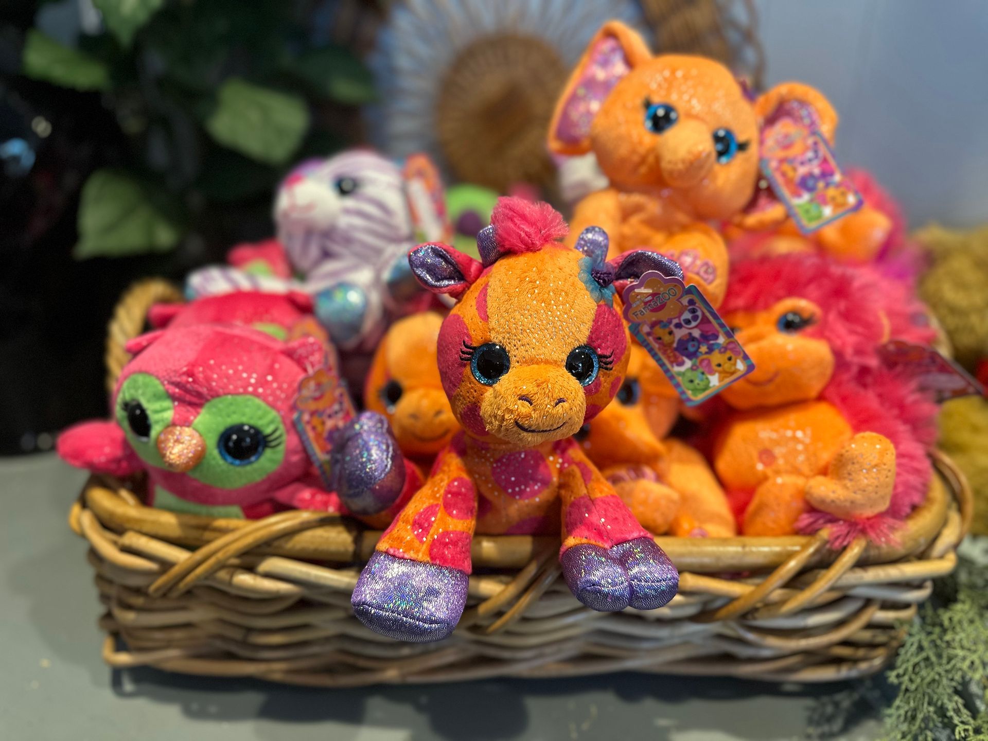 A basket filled with stuffed animals including a giraffe , owl , and cat.