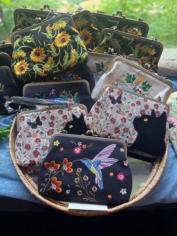 Floral embroidered coin purses and clutches displayed in a round basket.