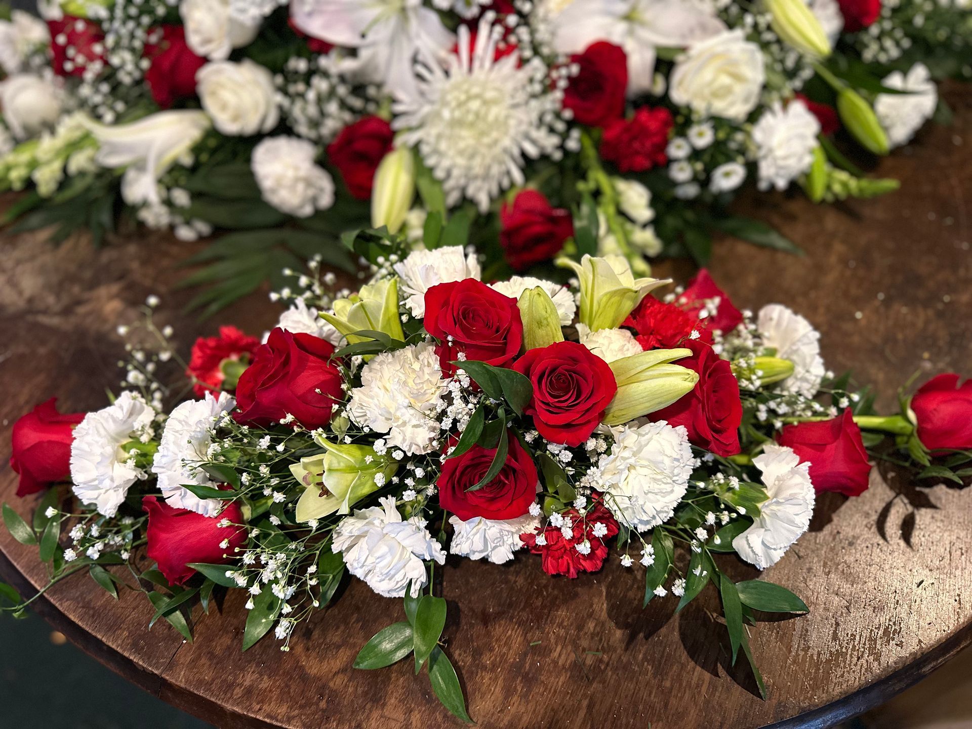 A table topped with red and white flowers and baby 's breath.