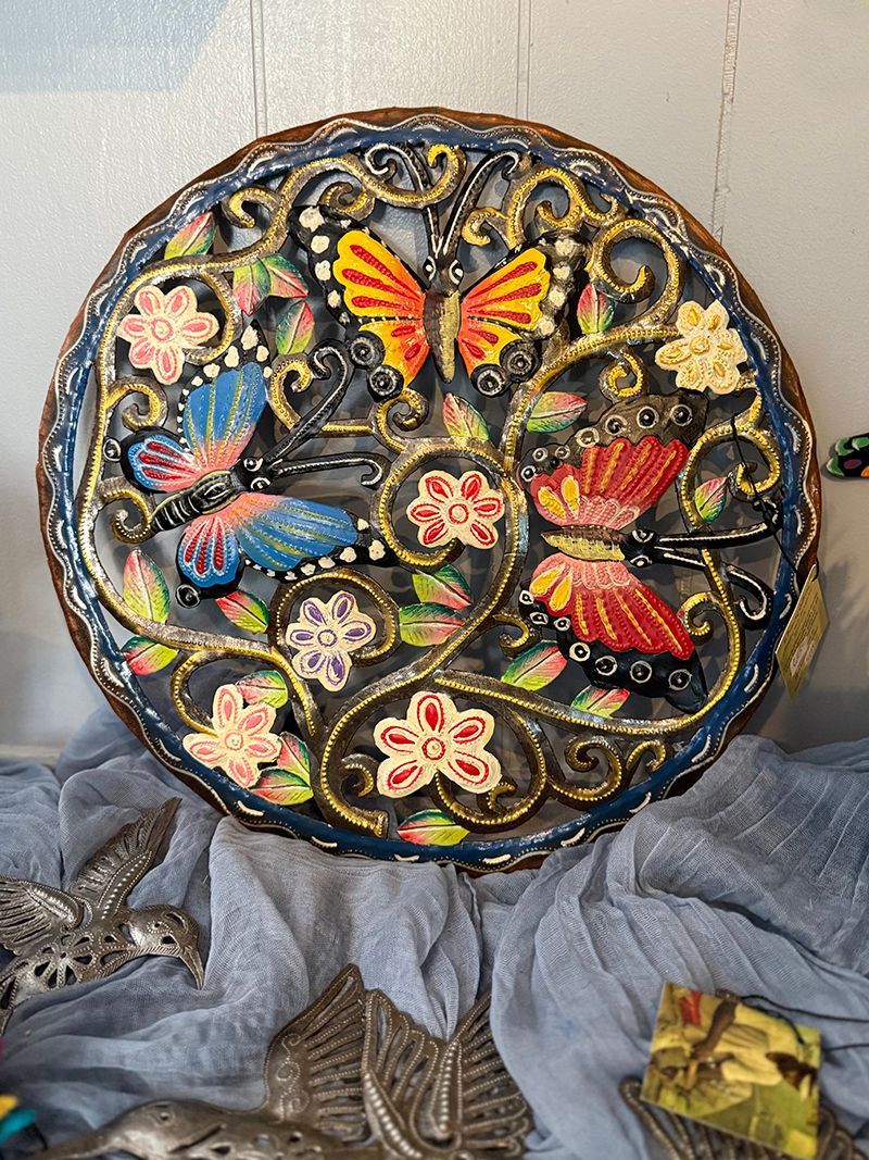 Round, metal wall hanging or garden decor with colorful butterflies and flowers.