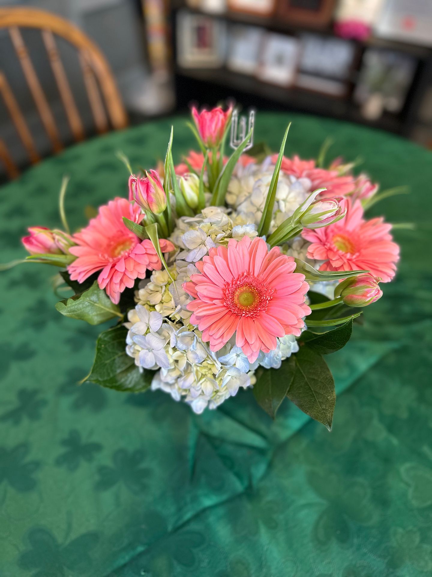 A vase filled with flowers and berries is sitting on a wooden table.
