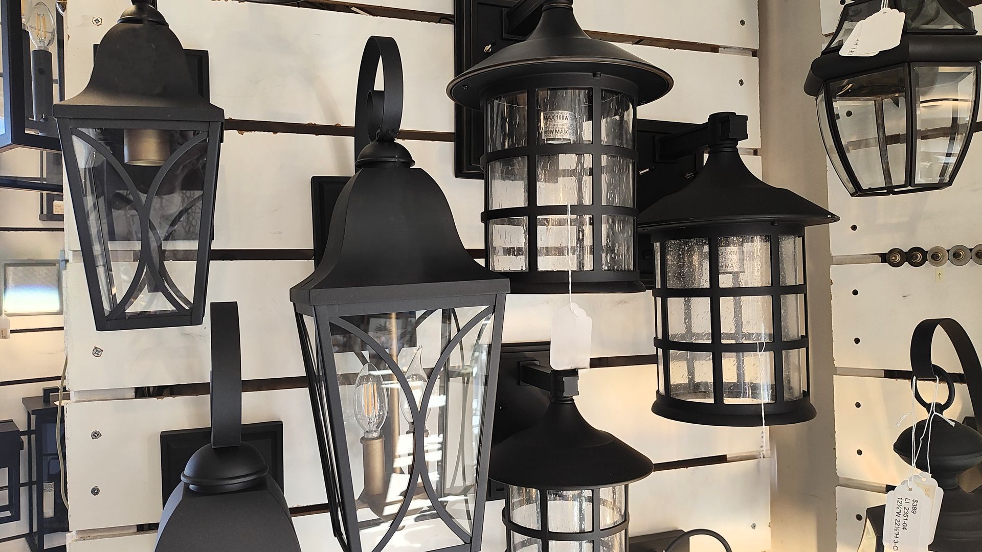 Assorted black outdoor lantern-style wall lights displayed on a store rack in Avon, CT